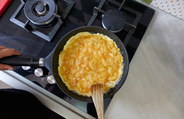 Spanish omelette cooking in a pan before turning it over