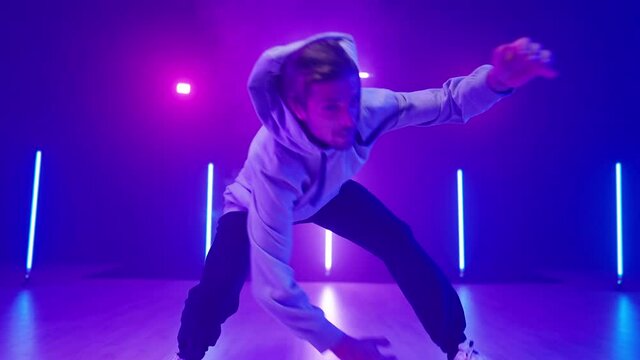 Young man breakdancing on neon lights dance floor in slow motion 4K