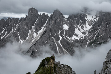 person looking on giant mountains covered with clouds 