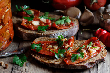 Dried tomatoes bread with oil, garlic and parsley, autumn traditional italian food - bruschetta or antipasti, closeup, healthy vegan food and simple living, rustic aesthetics concept
