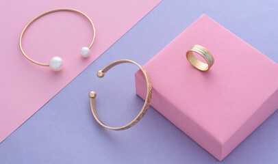 Top view of modern gold bracelets and ring on pastel colors paper background with copy space