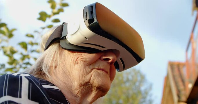portrait of an old woman in virtual reality glasses in the fresh air.close-up of a pensioner who is studying new technologies in a viar helmet. grandma discovering innovative technology in an