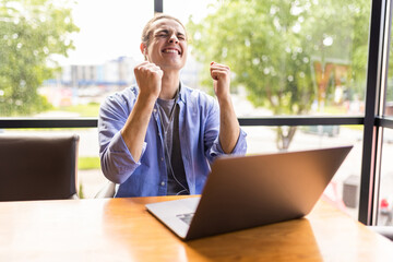 Overjoyed man celebrating victory in computer game enjoy playing on laptop computer during free...