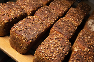 fresh brown loaves of rye bread in the form of bricks with sunflower seeds on a crust. Lie on a wooden rack