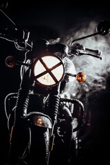 Fototapeta na wymiar Silhouette of black retro styled motorcycle scrambler at night in fog. Adventure, motor vehicle, custom motorbike concept. Dark night with haze