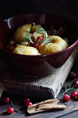 Baked apples, autumn or christmas winter dessert with cranberries, cinnamon, nuts and rosemary on dark moody background, closeup, healthy vegan holiday food concept