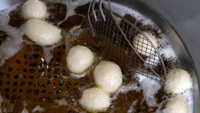 Slow motion of frying lokma dough in heated oil and mixing with sieve, traditional Greek sweet food, 