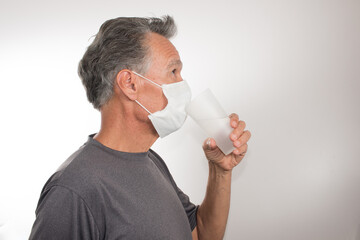 Man trying to Drink Water while still wearing his Surgical Mask