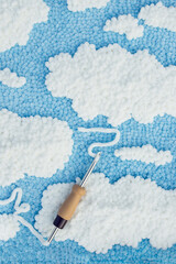 View of embroidered carpet of blue color with white spots and a punch needle with white velour...
