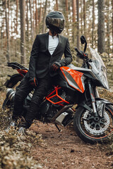 Fototapeta na wymiar Man weared in black suit with dark motorcycle in forest