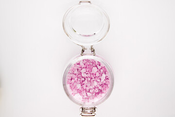 A jar with soft pink granules of sea salt in a transparent glass jar