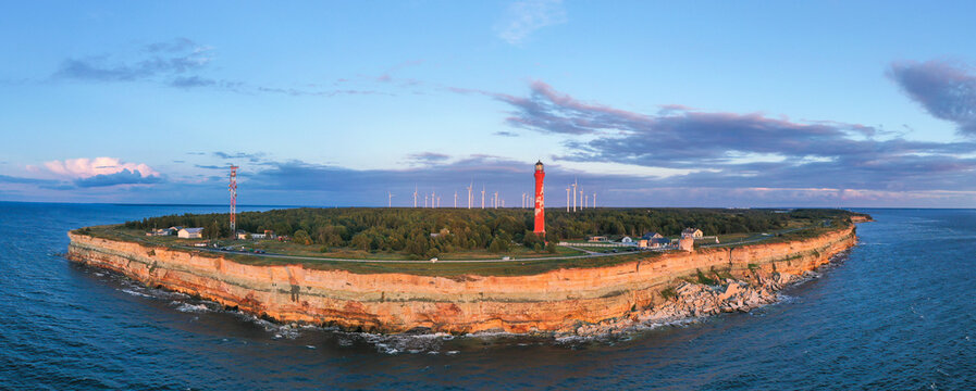 Sunset colored limestone cliff on Pakri peninsula, Estonia with the historic lighthouses and wind farm  on the background
