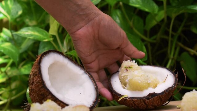 Close up shot of hand putting sweet coconut balls on wooden table. Traditional Indian sweet also known as Kopra pak.