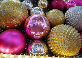 large shiny gold textured round, pink and gold christmas toys hanging on the Christmas tree