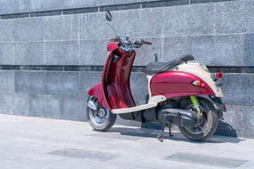 Fototapeta na wymiar a red scooter standing against a stone wall