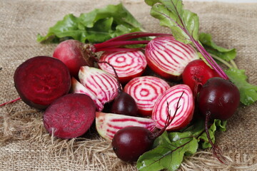 Pieces of beets in a ceramic plate on a background of burlap. Striped chioggia beetroot and regular red beetroot.

