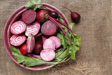 Pieces of beets in a ceramic plate on a background of burlap. Striped chioggia beetroot and regular red beetroot.
