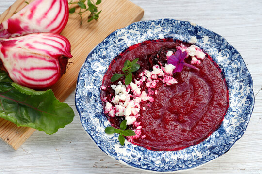 Beetroot puree soup sprinkled with beetroot chips and feta cheese crumbs