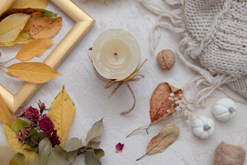 Fototapeta na wymiar Autumn vintage still life top view with fallen leaves, dry rose, candles and knitted blanket. Autumn atmosphere concept