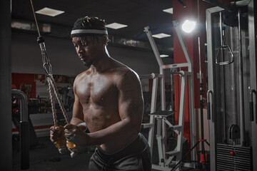 Fototapeta na wymiar Concentrated african american sportsman training muscles in gym. Motivated bodybuilder on workout