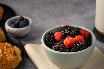 Breakfast with croissant, coffee and berries against gray background