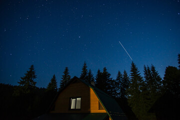 Beautiful night landscape, house among the forest against the background of the starry sky