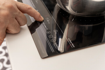 Man's finger raising the temperature in an induction hob