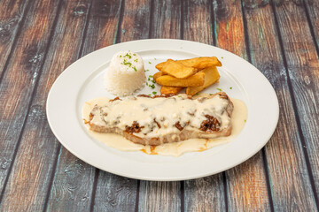 steak with pepper slathered in sauce garnished with homemade fries and a bowl of white rice