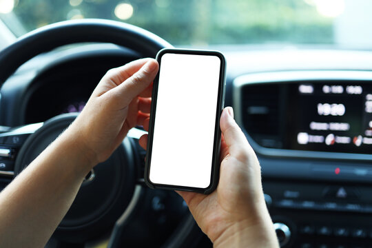 Mock up image, girl using blank white screen mobile smart phone inside a car in sunny day, touching screen or texting, copy space for your advertisement