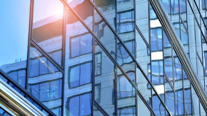 Fototapeta premium View of office building with glass wall under blue sky. Architecture details of business background.