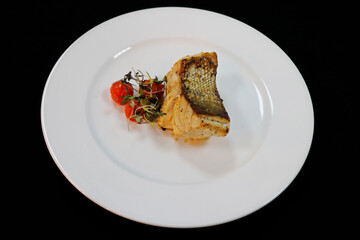 grilled atlantic cod fish fillet on a white plate with cherry tomato