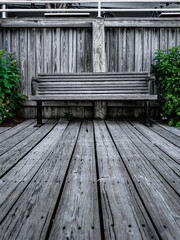 Weathered wooden deck and bench with green plants. Retro Cape Cod Style yard deck.