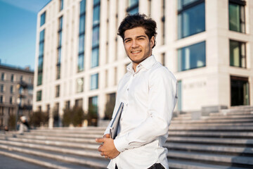 The manager goes to work in the office. A male entrepreneur is standing holding a laptop in his hands. A smart broker is an investor in a business suit.