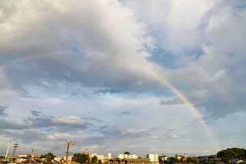 雨上がりの雲の合間から見える青空と大きく架かる虹の橋