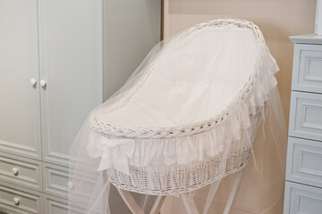 Fototapeta na wymiar White traditional old fashioned wicker baby crib cot . Vintage baby wicker. Nice Wicker cradle for a newborn. Baby room