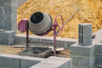 Concrete block on building wall. Concrete mixer in construction site.