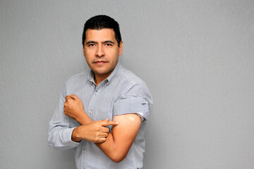 Adult Latino man showing his arm where he received the Covid-19 vaccine in the new normal
