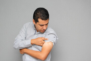 Adult Latino man showing his arm where he received the Covid-19 vaccine in the new normal
