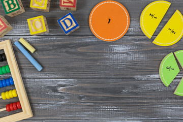 Multicolored fractions, blocks on gray wooden table. Back to school, fun math, games for kindergarten, preschool education.