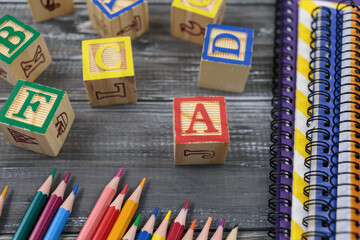 Wooden alphabet blocks on wooden background. Back to school, games for kindergarten, preschool education. Abacus, pencils, notebooks, blocks on the table.