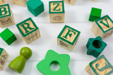 Green wooden alphabet blocks on a white wooden table. Back to school, games for kindergarten, preschool education.