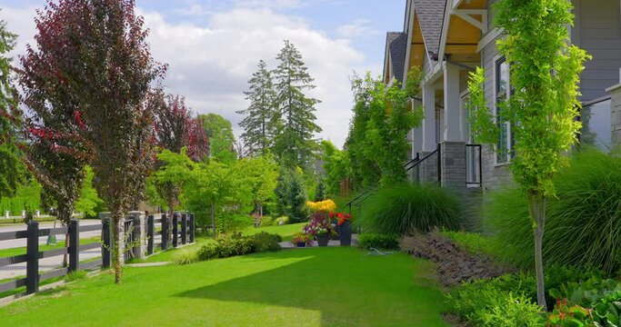 Establishing shot. Neighbourhood of luxury houses with street road, big trees and nice landscape in Vancouver, Canada. Blue sky. Day time on June 2021. Still camera view. ProRes 422 HQ.