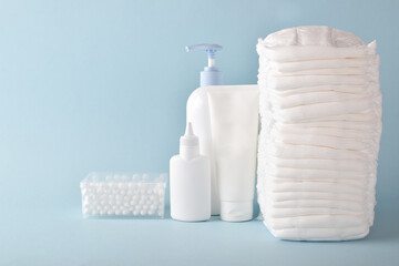 Various accessories for children's hygiene. A large stack of diapers next to them are bottles of baby cosmetics.