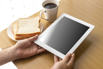  朝食を食べながら、タブレット端末を使う、男性の手イメージ