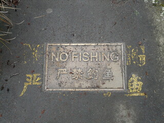 No fishing sign embedded in the concrete sidewalk