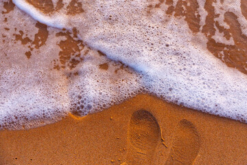 Sea waves and foam in sandy beach in evening.