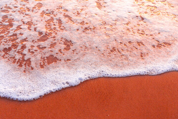 Sea waves and foam in sandy beach in evening.