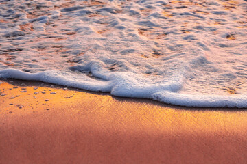 Sea waves and foam in sandy beach in evening.