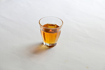 Closeup of Honey in a small glass laid on a white background. Healthy food concept, selective soft focus.