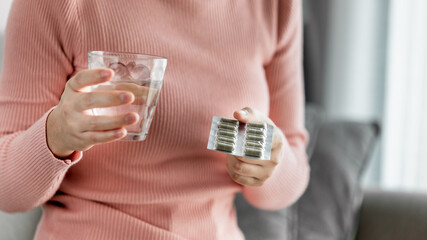 Close up of Young women holding Andrographis paniculata(Kariyat)capsules pack and glass of water, Home Isolation, Initial treatment for COVID-19 infection, Health Care Concept.